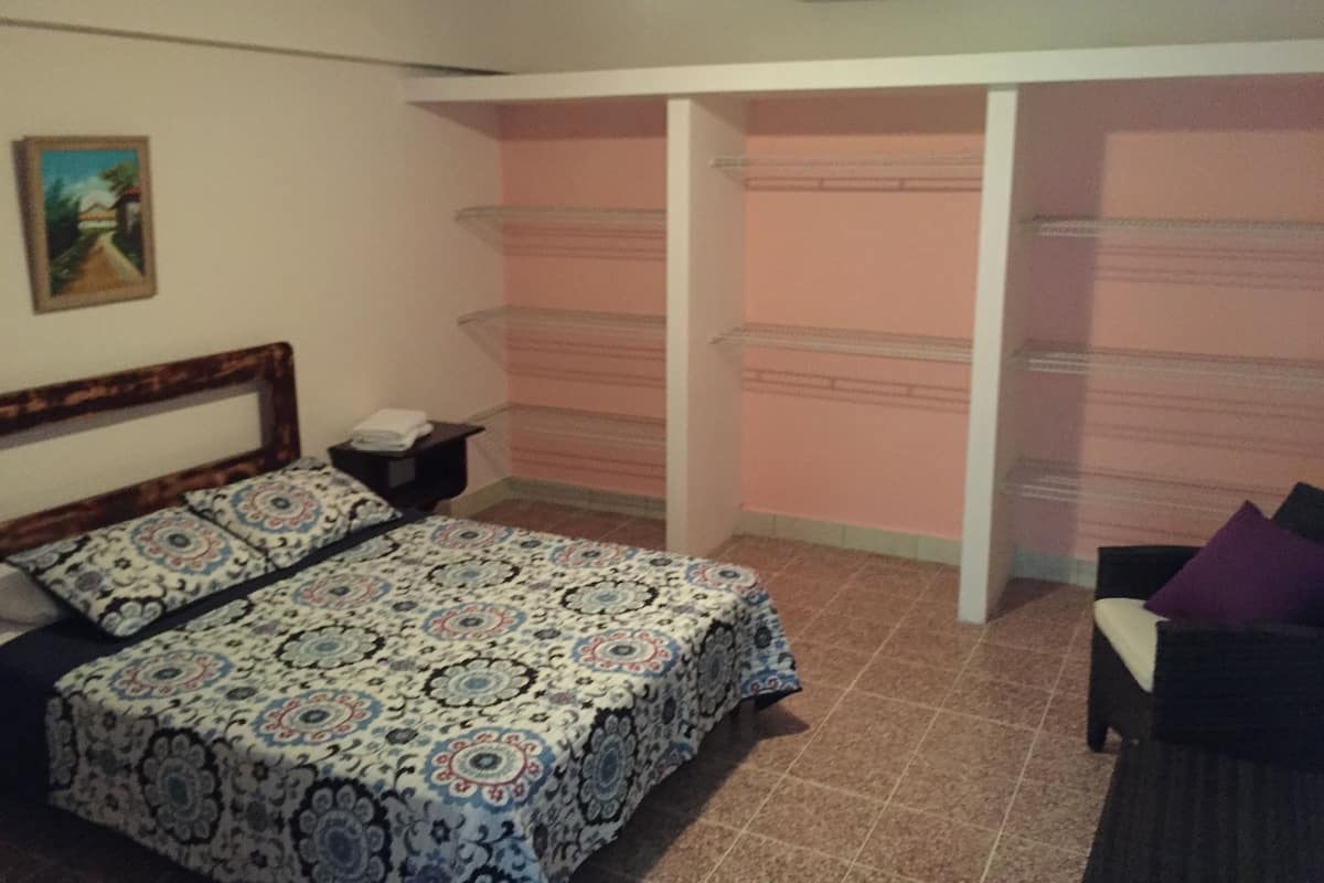 Un dormitorio con cama, mesita de noche, silla y armario.