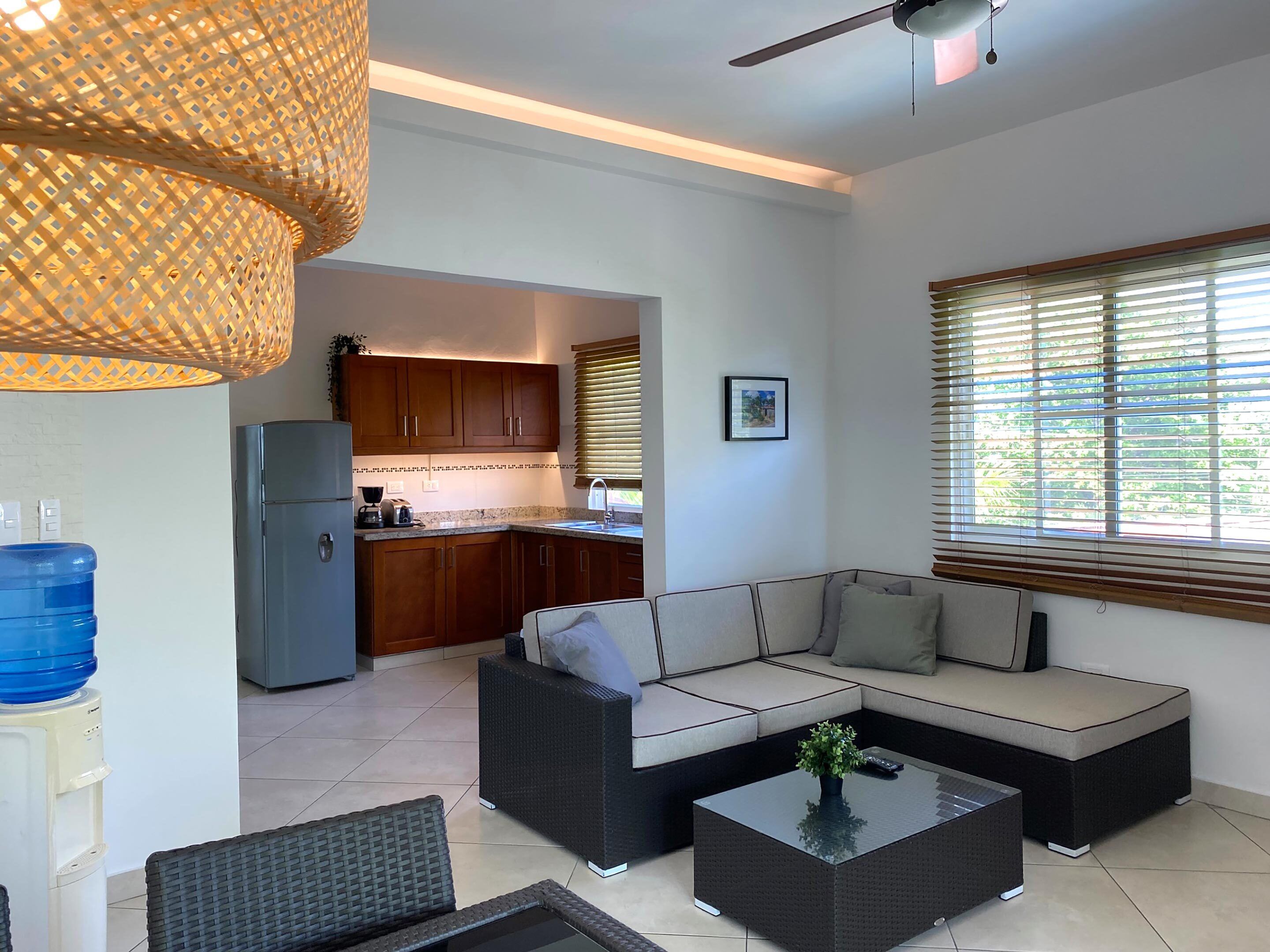 A modern living room with a sectional sofa, a coffee table, and a kitchen in the background.