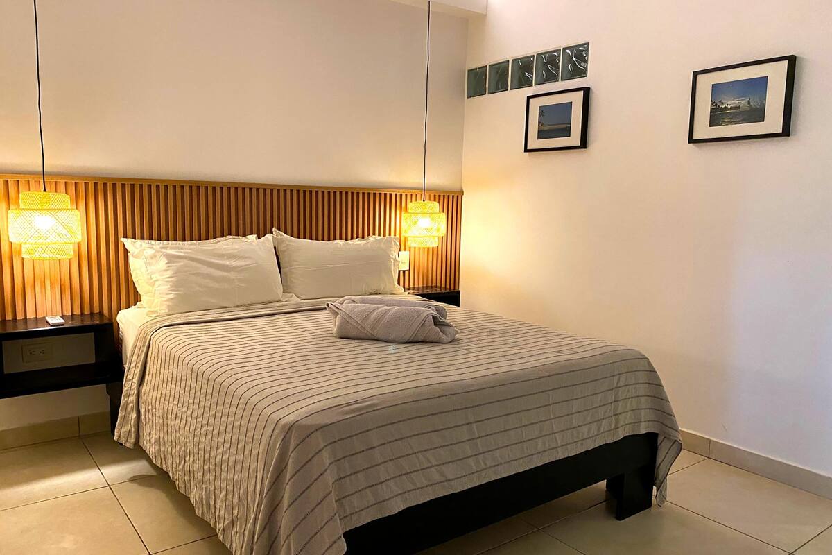 A neatly made bed with a striped bedspread, two bedside lamps, and a wooden headboard.