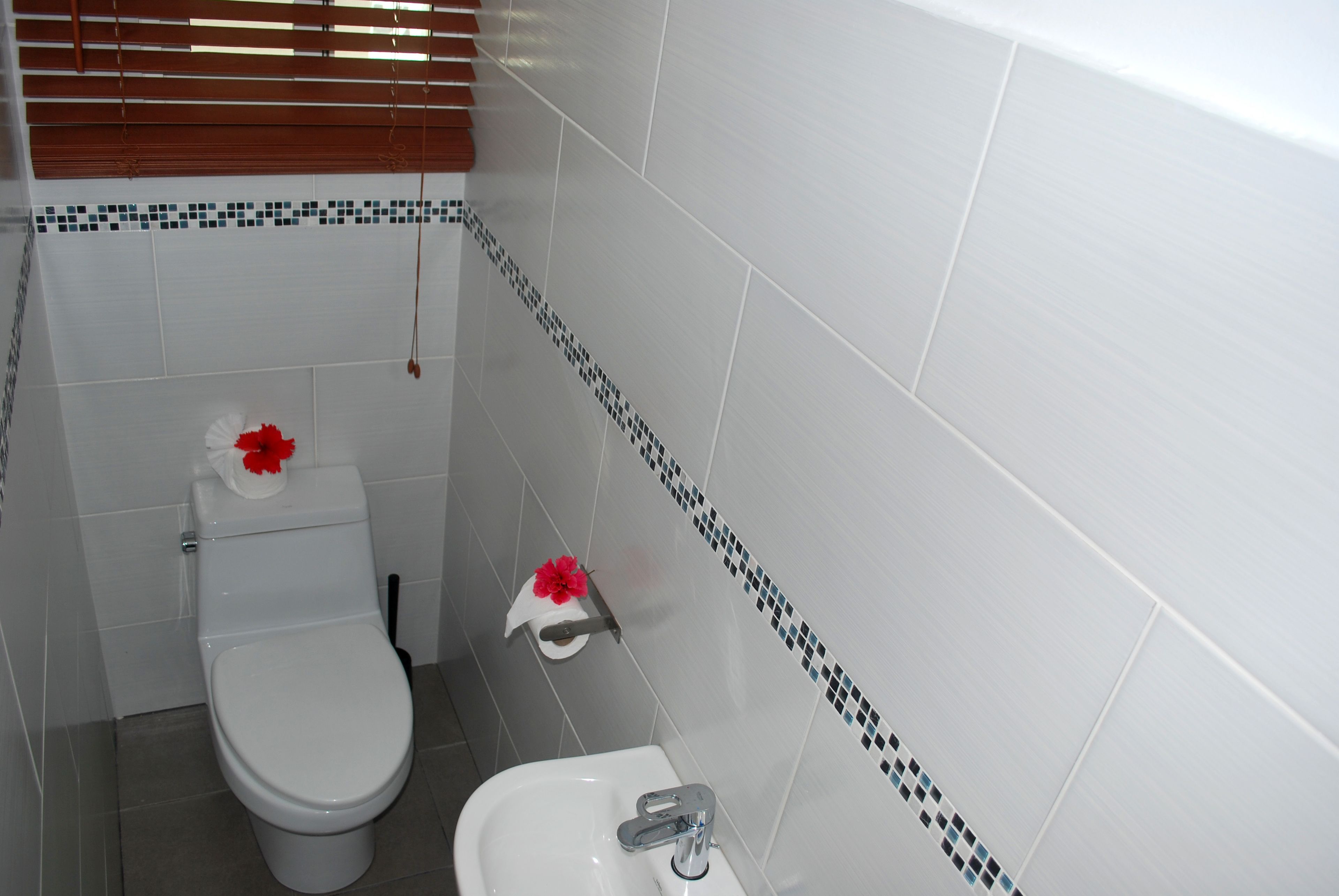 A bathroom with a toilet, sink, and a decorative tile border.