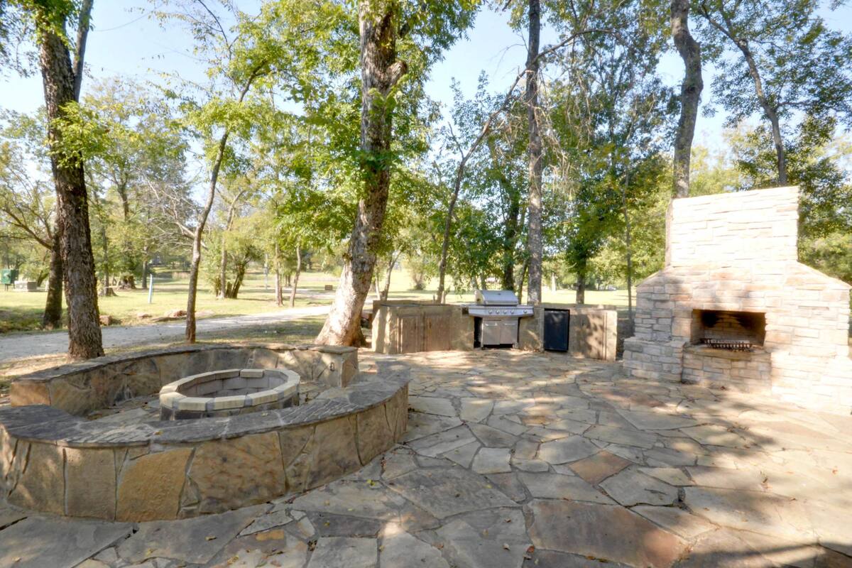 An outdoor patio with stone flooring, a stone fire pit, and a stone fireplace.