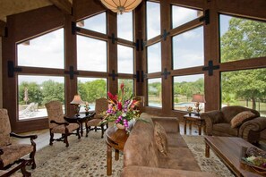 A spacious living room with large windows, a fireplace, and a view of the outdoors. - Mill Creek Ranch Resort (Canton)