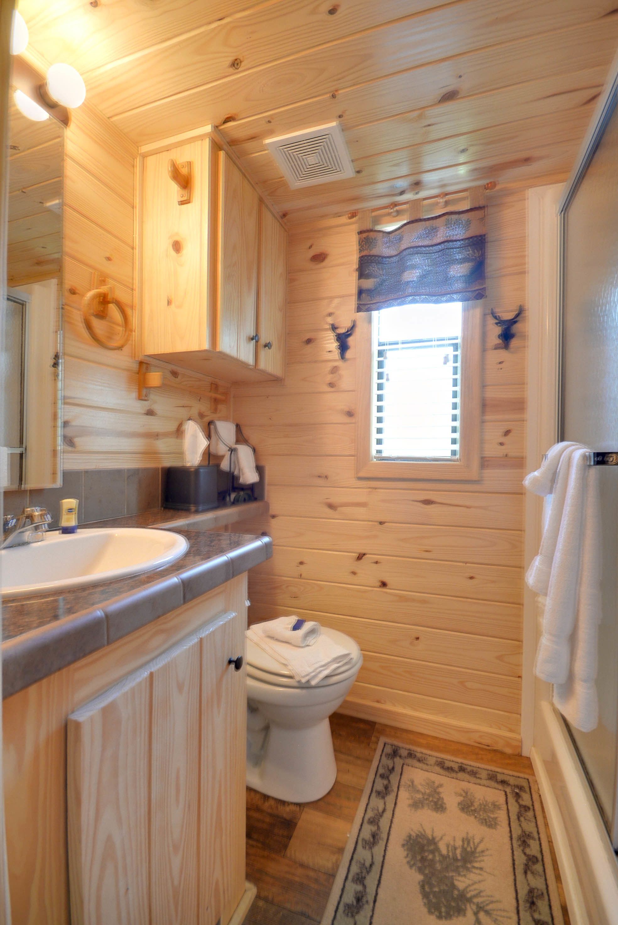 Ein Badezimmer einer Holzhütte mit Waschbecken, Toilette und Fenster.