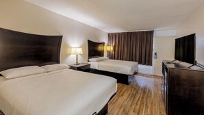 A hotel room with two beds, a desk, a TV, and a bathroom.