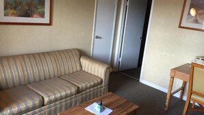 A hotel room with a striped sofa, a wooden table, and two doors.