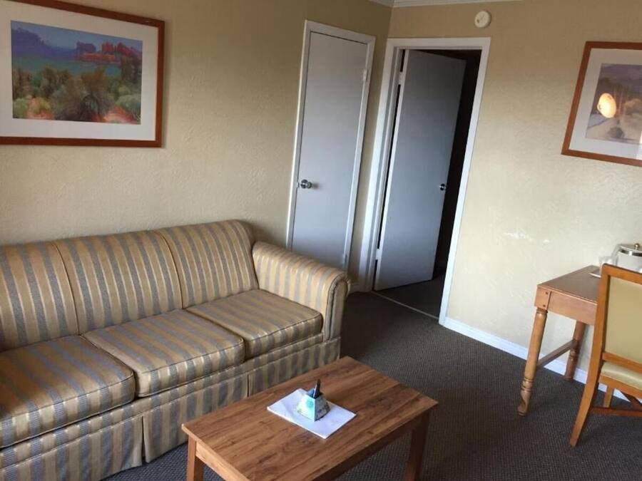 Ein Hotelzimmer mit einem gestreiften Sofa, einem Holztisch und zwei Türen.