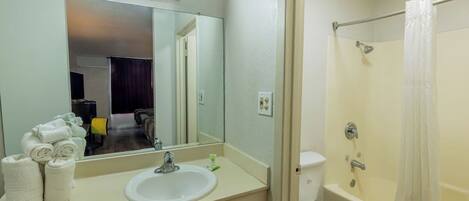 A bathroom with a sink, mirror, toilet, and shower.