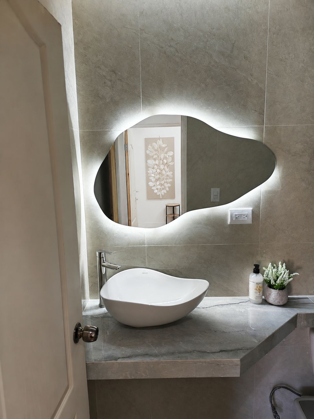 A bathroom with a modern sink, a wall-mounted mirror, and a potted plant.