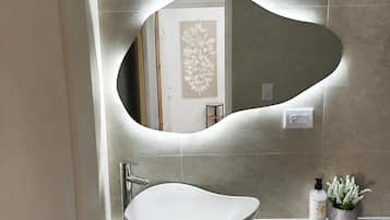 A bathroom with a modern sink, a wall-mounted mirror, and a potted plant.