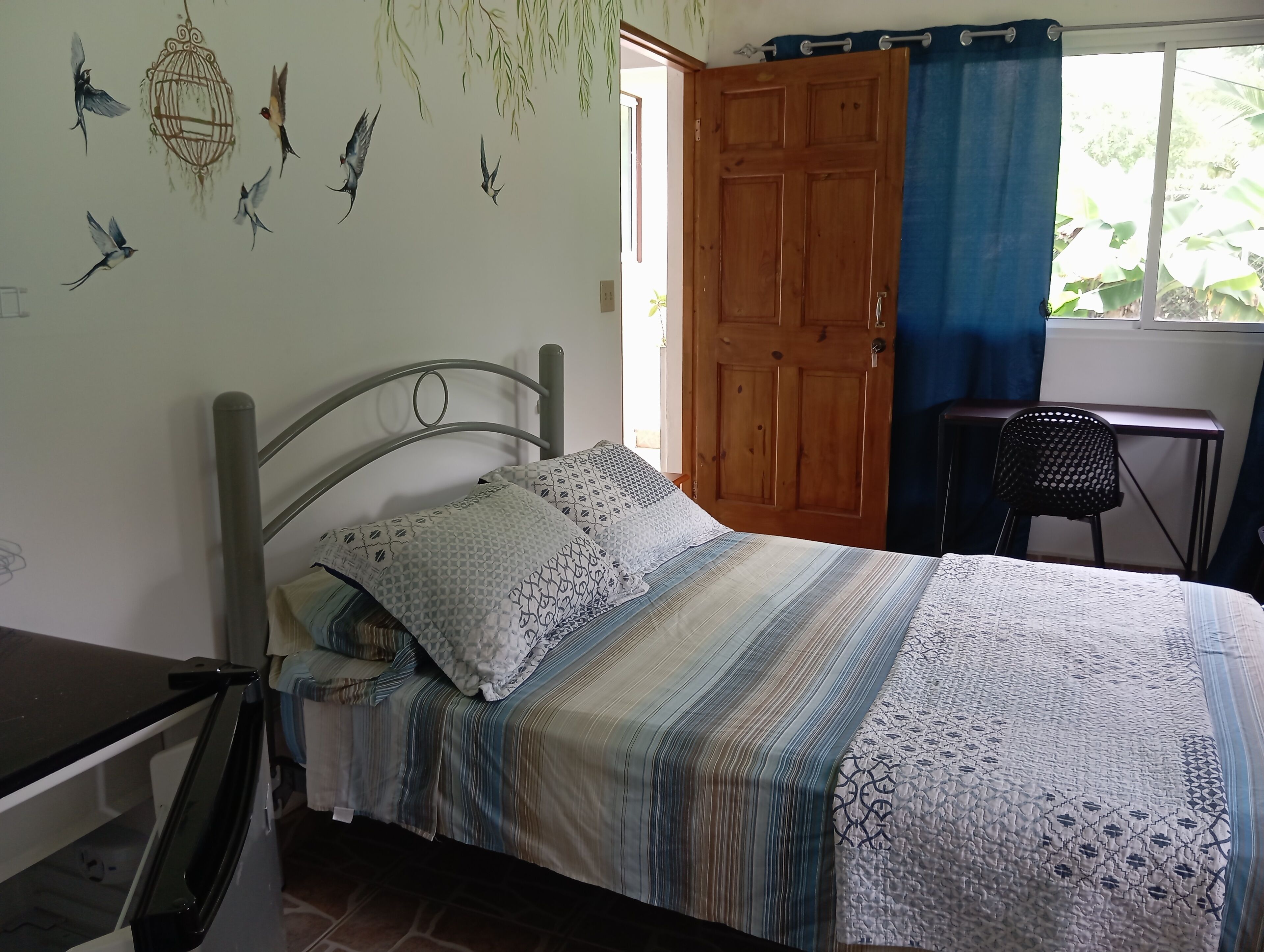 A bedroom with a bed, a desk, and a chair.
