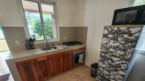 A kitchen with a sink, stove, oven, and a refrigerator with a marble pattern. - Little Italy B&B (Tijeras)