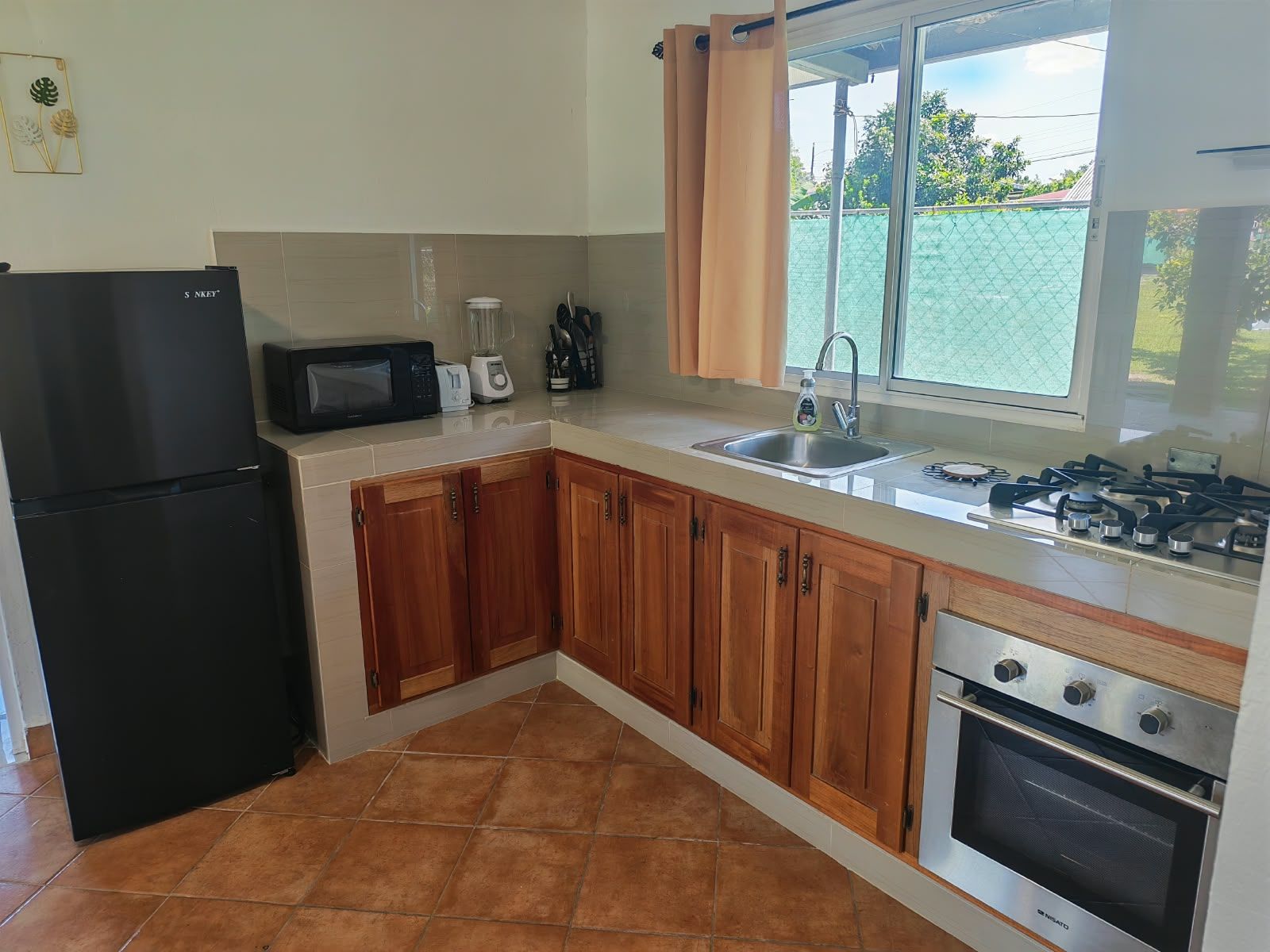 A kitchen with a refrigerator, microwave, toaster, sink, and stove.