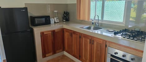 A kitchen with a refrigerator, microwave, toaster, sink, and stove.