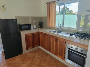 A kitchen with a refrigerator, microwave, toaster, sink, and stove. - Little Italy B&B (Tijeras)