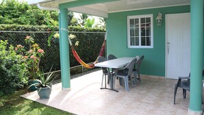 A covered patio with a table and chairs, a door, and a hammock. - Little Italy B&B (Tijeras)