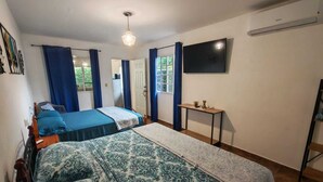 A bedroom with two beds, a TV, and a small table. - Little Italy B&B (Tijeras)