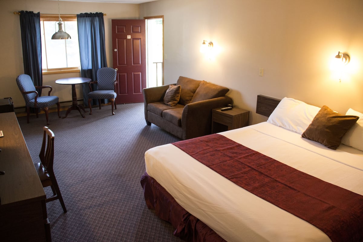 Une chambre d’hôtel avec un grand lit, un canapé, deux fauteuils, une petite table et un bureau.