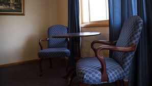 A room with two patterned armchairs, a small round table, and a painting on the wall. - Fran Cove Motel (Lake George)