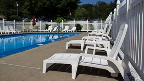 A swimming pool with white lounge chairs and a white picket fence. - Fran Cove Motel (Lake George)
