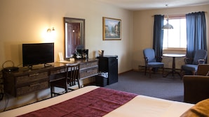 A hotel room with a bed, a desk with a computer, a chair, a small table, and a window with curtains. - Fran Cove Motel (Lake George)