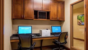 A hotel office with two desks, computers, chairs, and a printer.