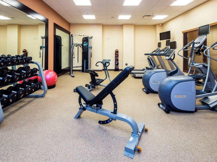 A gym with exercise equipment, including treadmills, a bench, and dumbbells.