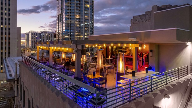 An outdoor rooftop bar with tables and chairs, surrounded by high-rise buildings. - Hilton Garden Inn Phoenix Downtown (Phoenix)