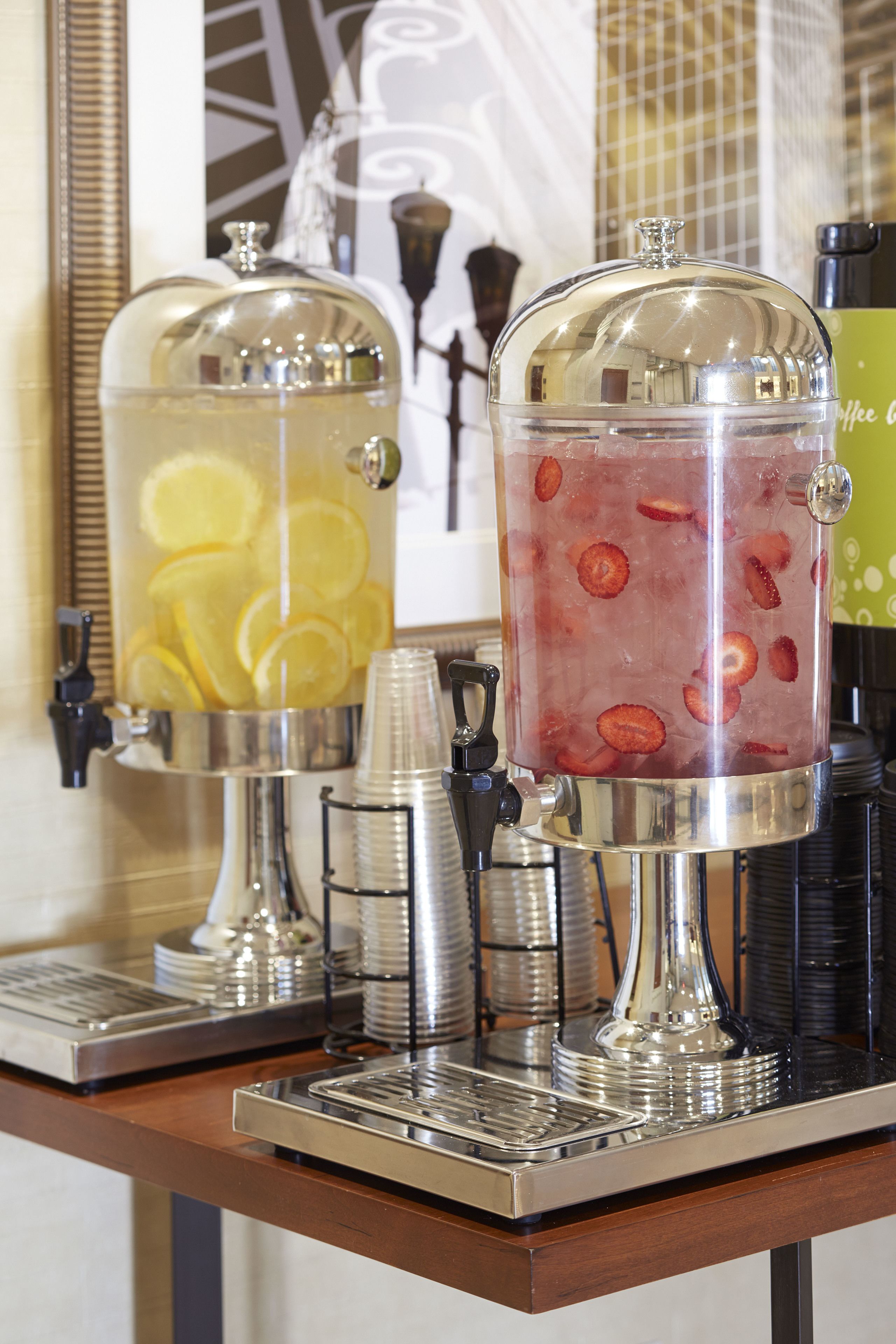 A beverage dispenser with two sections, one containing lemon slices and the other with strawberry slices.
