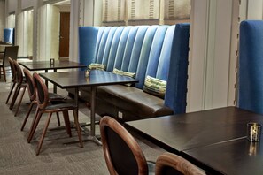 A hotel dining area with long tables, wooden chairs, and blue cushioned booths. - Hilton Garden Inn Phoenix Downtown (Phoenix)