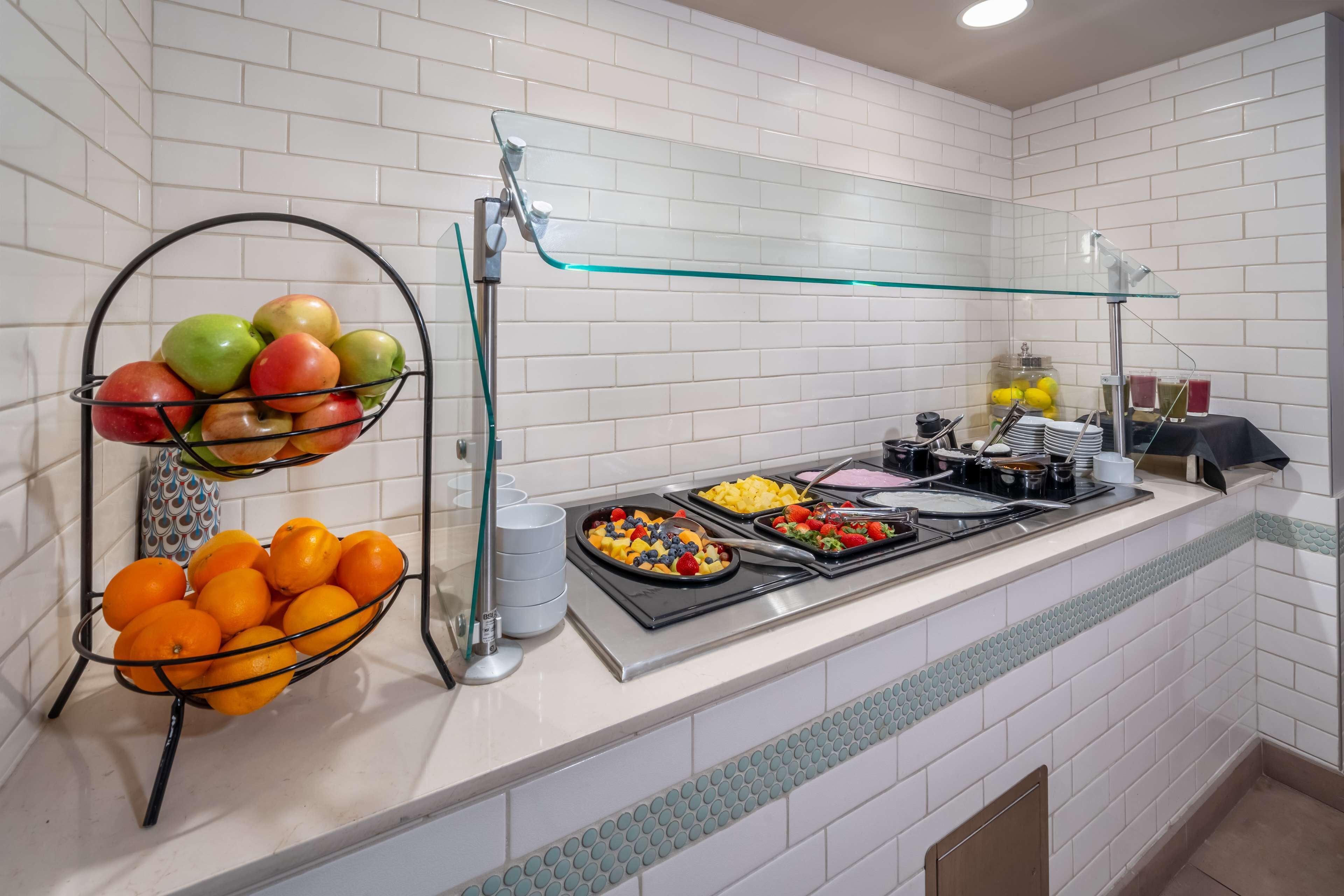 A breakfast buffet with fruit bowls and a variety of breakfast items.