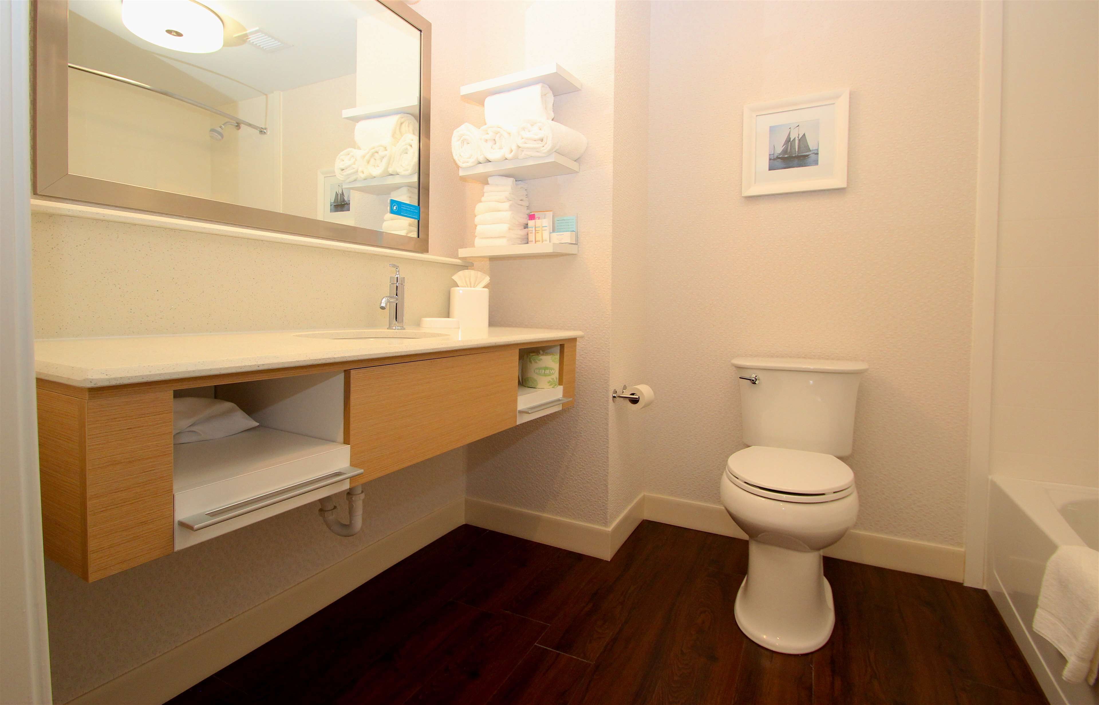 A bathroom with a wooden vanity, a toilet, a bathtub, and a mirror.