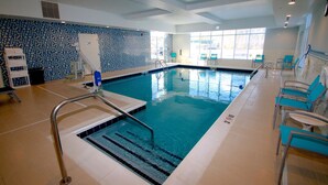 An indoor swimming pool with clear lane markings, a lifeguard chair, and a blue tiled wall. - Hampton Inn Suffolk (Suffolk)