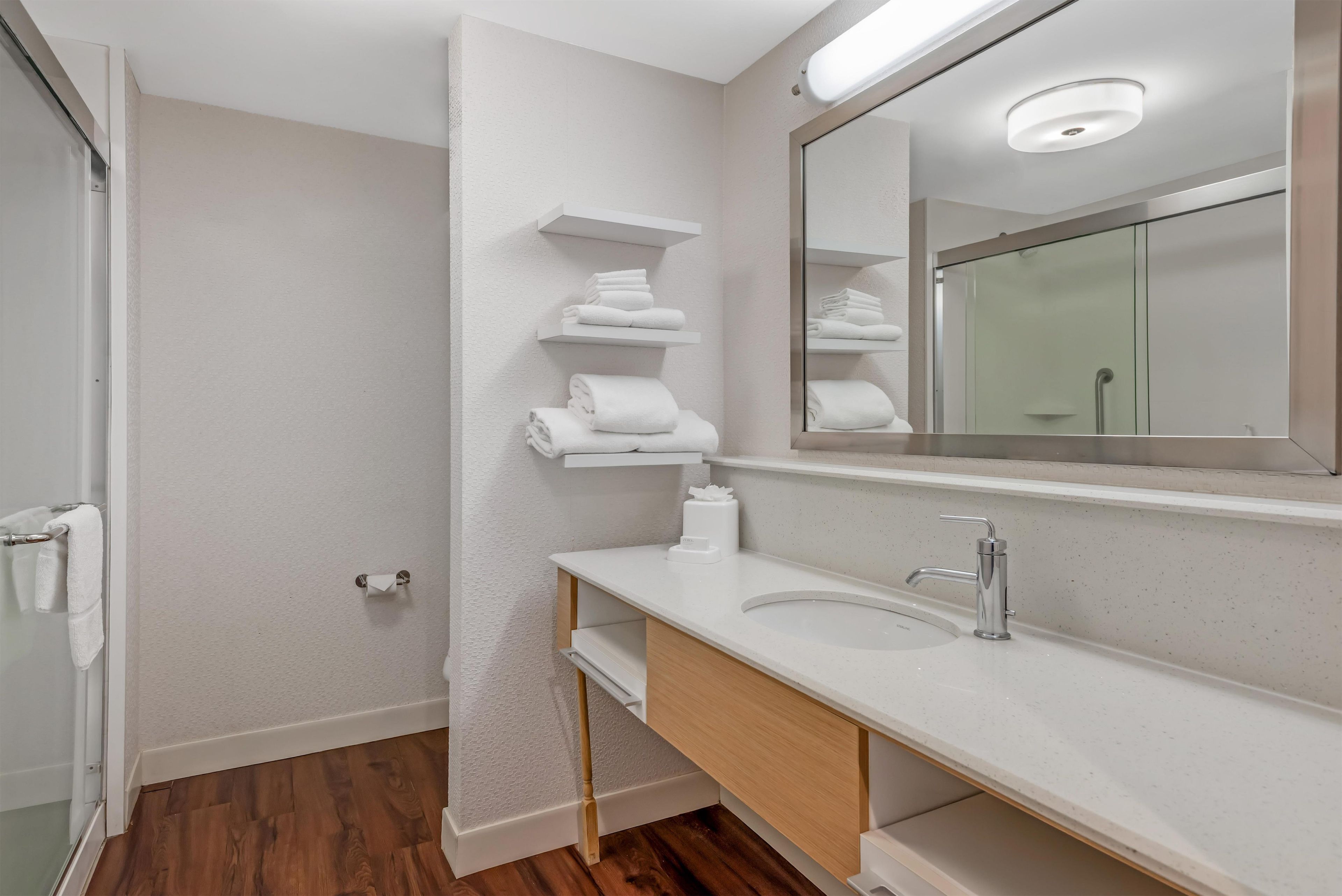 A modern bathroom with a white sink, a mirror, and a towel rack.