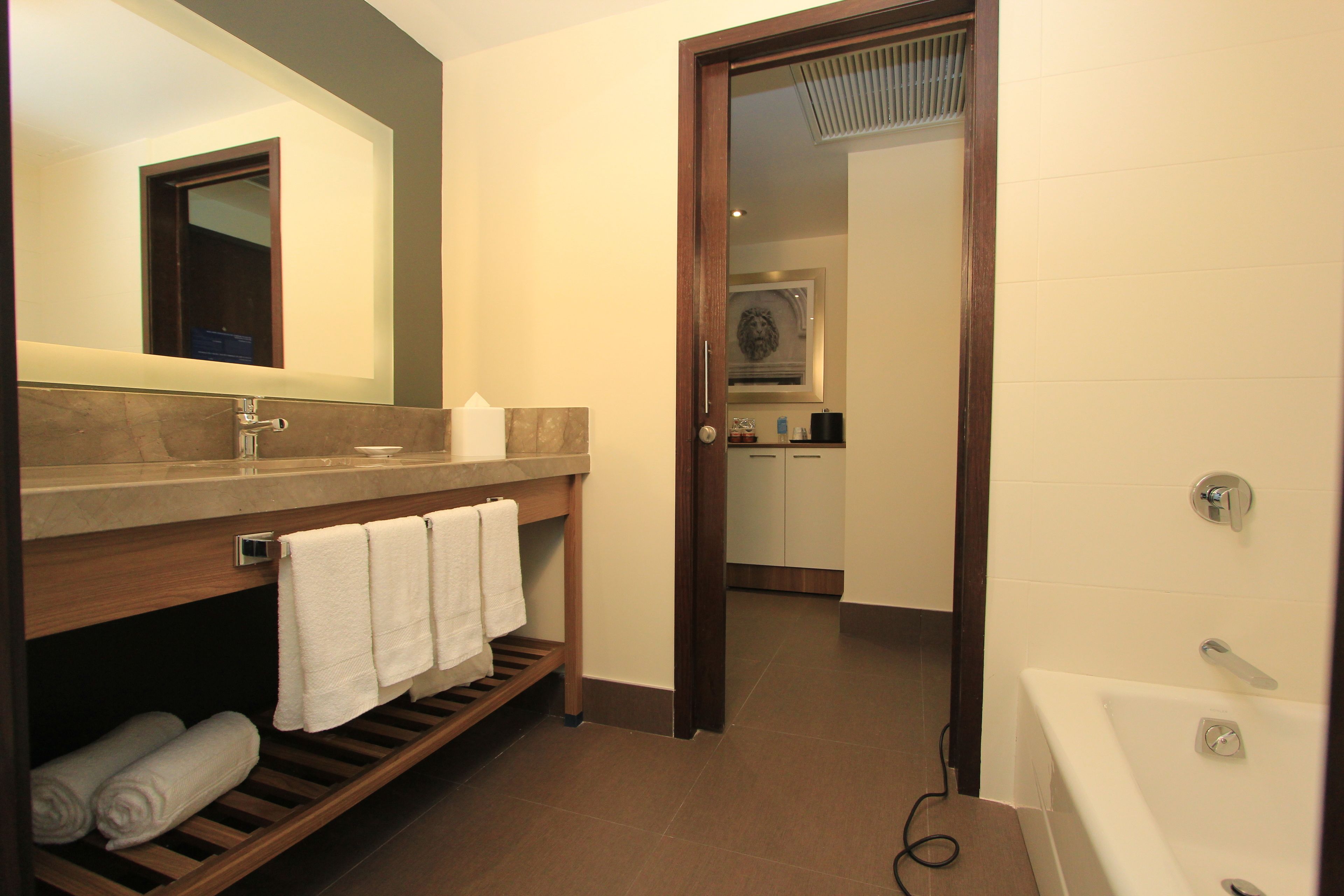A modern bathroom with a wooden vanity, a large mirror, a bathtub, and a shower.