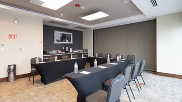 A conference room with a long table, chairs, water bottles, a projector, and a fire extinguisher.