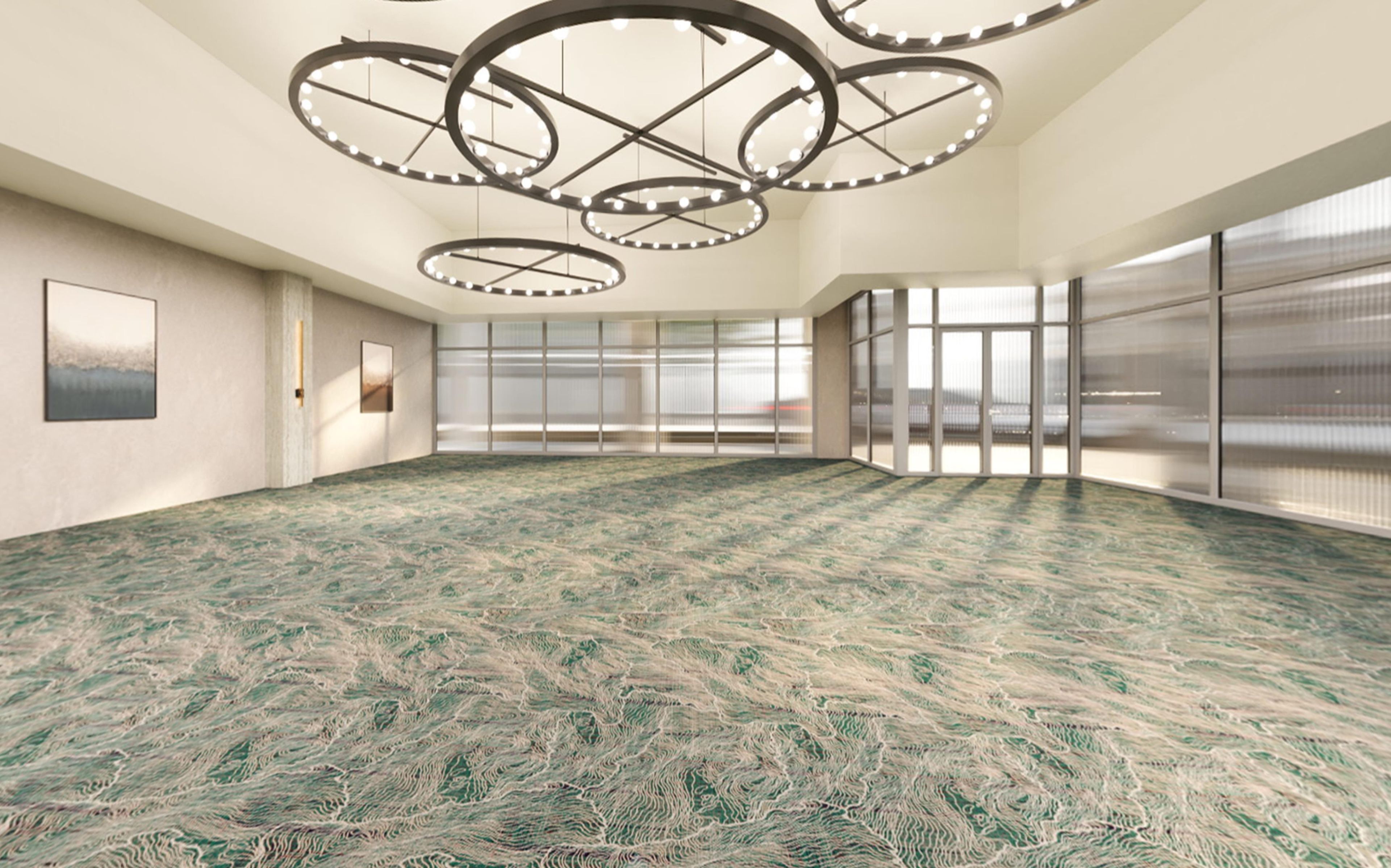 A spacious room with a patterned carpet, large windows, and a unique circular ceiling light fixture.