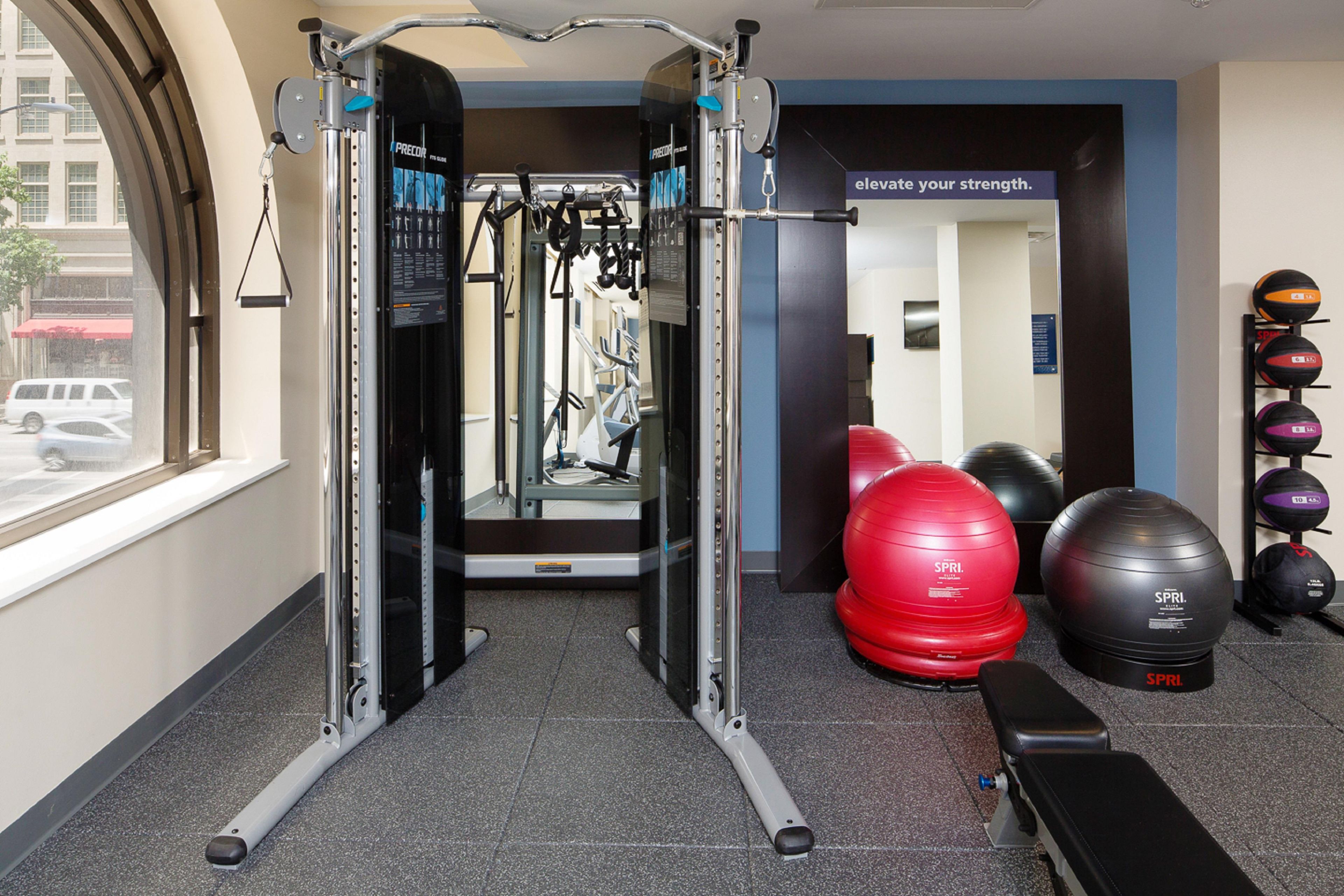 A gym with exercise equipment, a bench, and exercise balls.