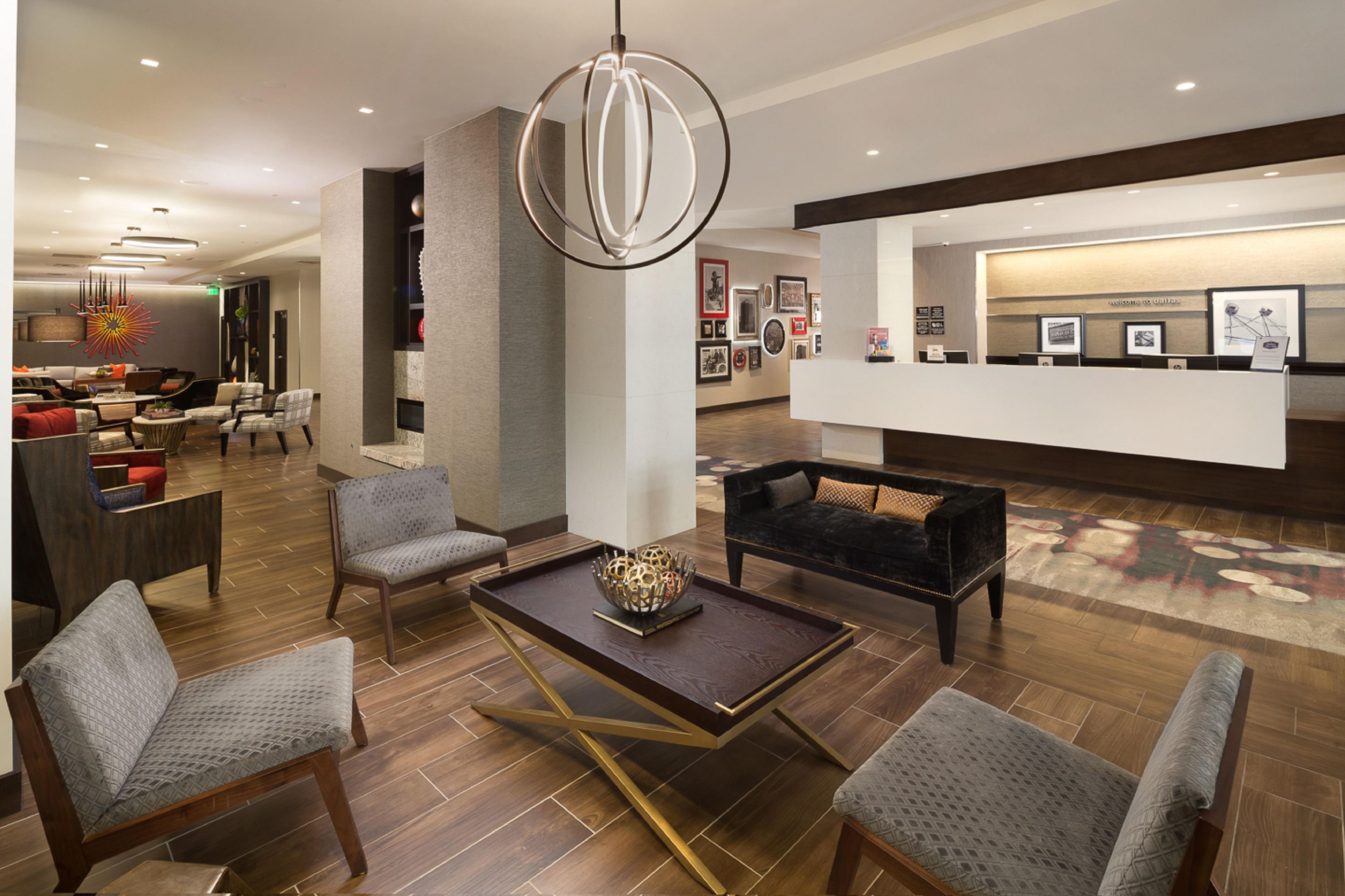 Un vestíbulo moderno con una recepción, zona de estar y una lámpara decorativa.