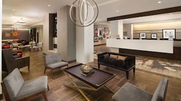 Un vestíbulo moderno con una recepción, zona de estar y una lámpara decorativa.