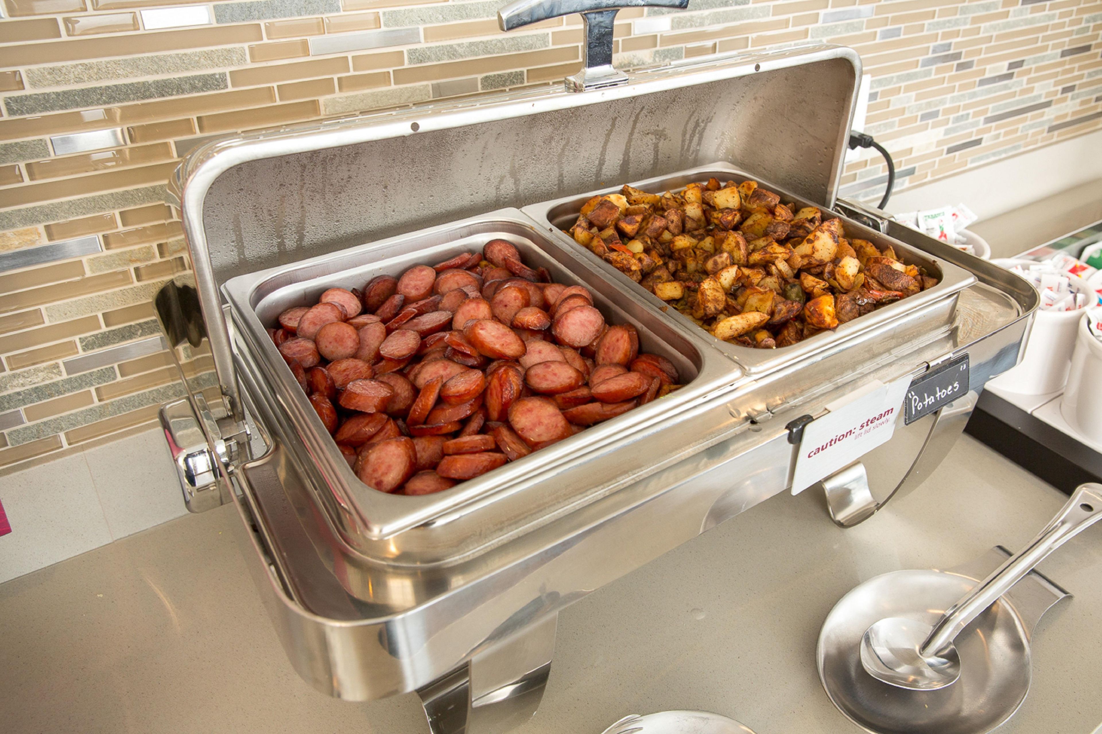 Un buffet avec deux plateaux en métal, l’un portant l’inscription « Porc » et l’autre « Pommes de terre ».