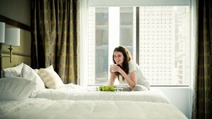 A hotel room with a large bed, a nightstand with a lamp, and a window with a view of buildings. - Hampton Inn & Suites Dallas Downtown (Dallas)