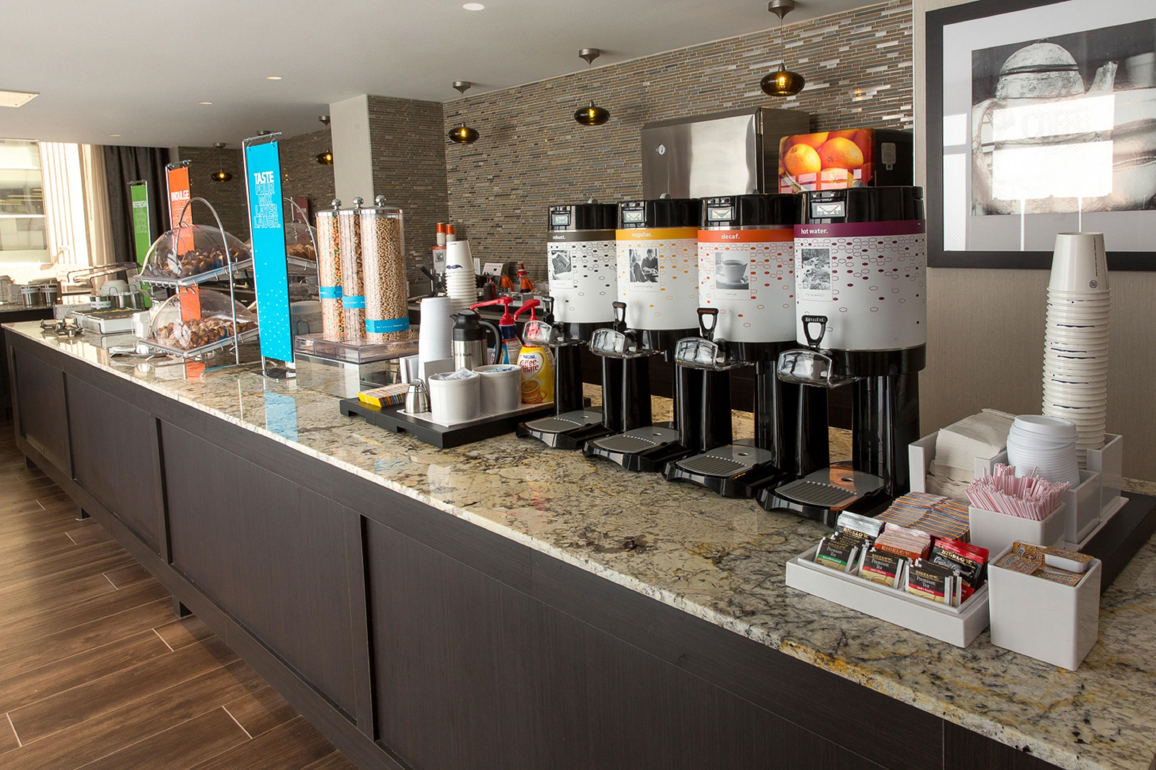 A self-service beverage station with multiple dispensers, including hot water, coffee, and tea options.
