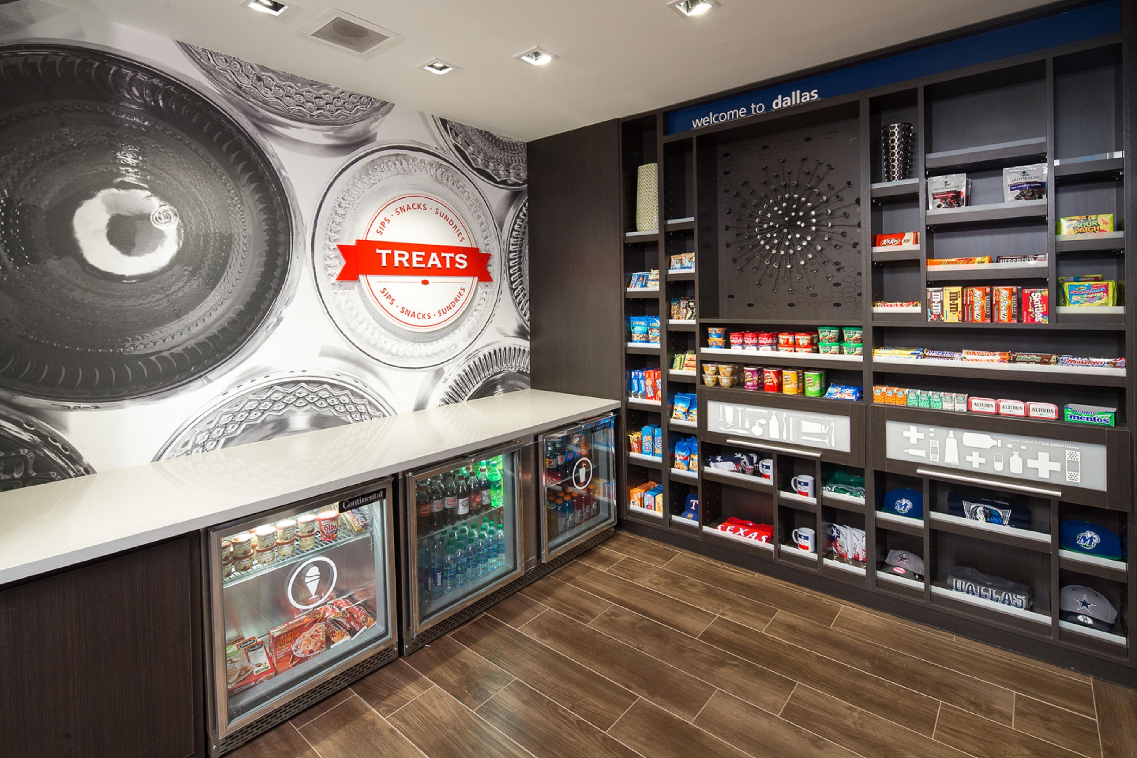 Un bar à collations avec une enseigne indiquant « Friandises », des étagères remplies de snacks et une autre enseigne au-dessus qui dit « Bienvenue à Dallas ».