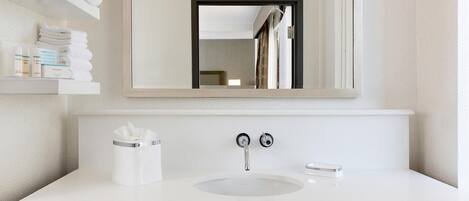A bathroom with a white sink, a mirror, a towel rack, and a tissue box.