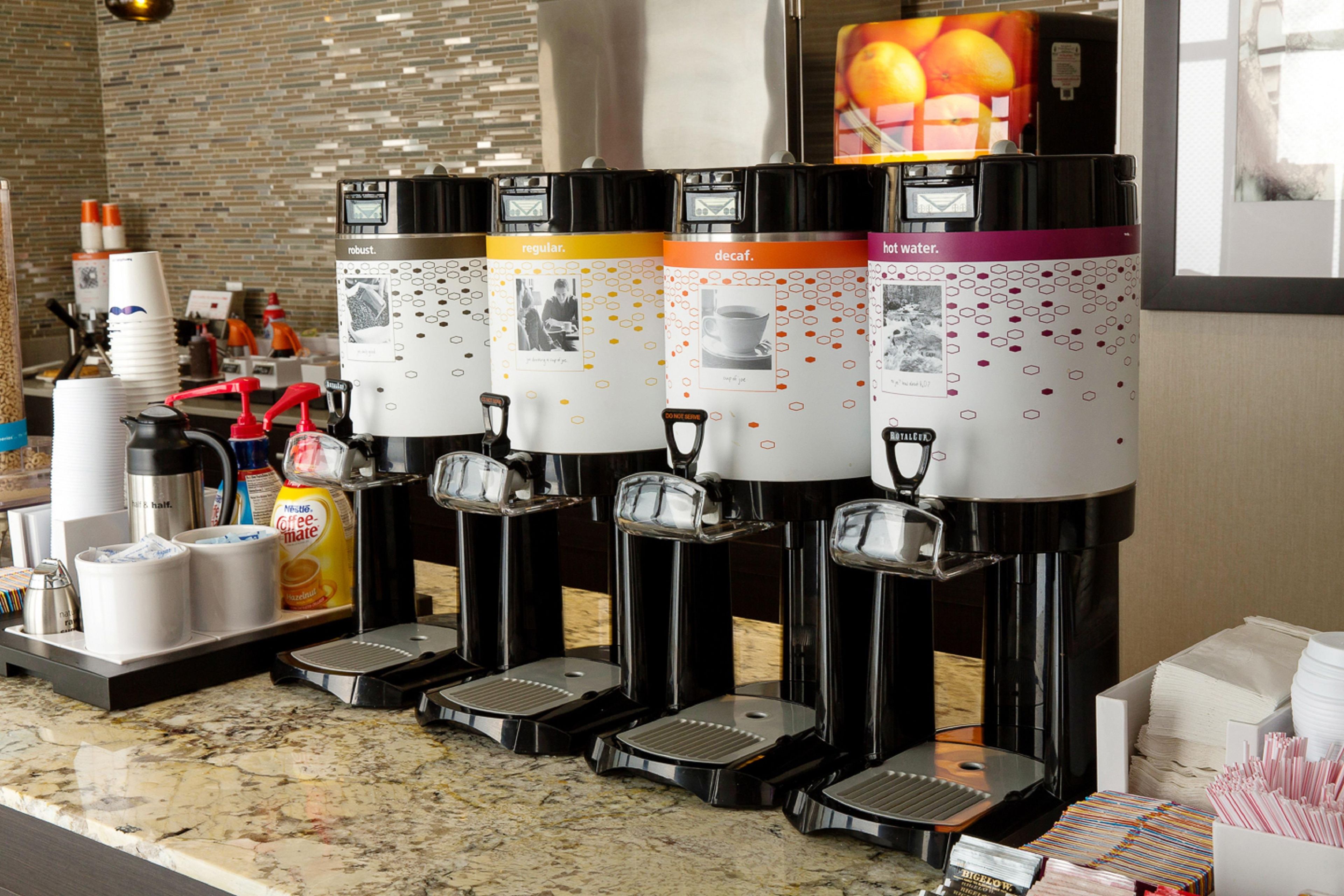 A coffee station with multiple dispensers, a coffee machine, and a variety of coffee pods.