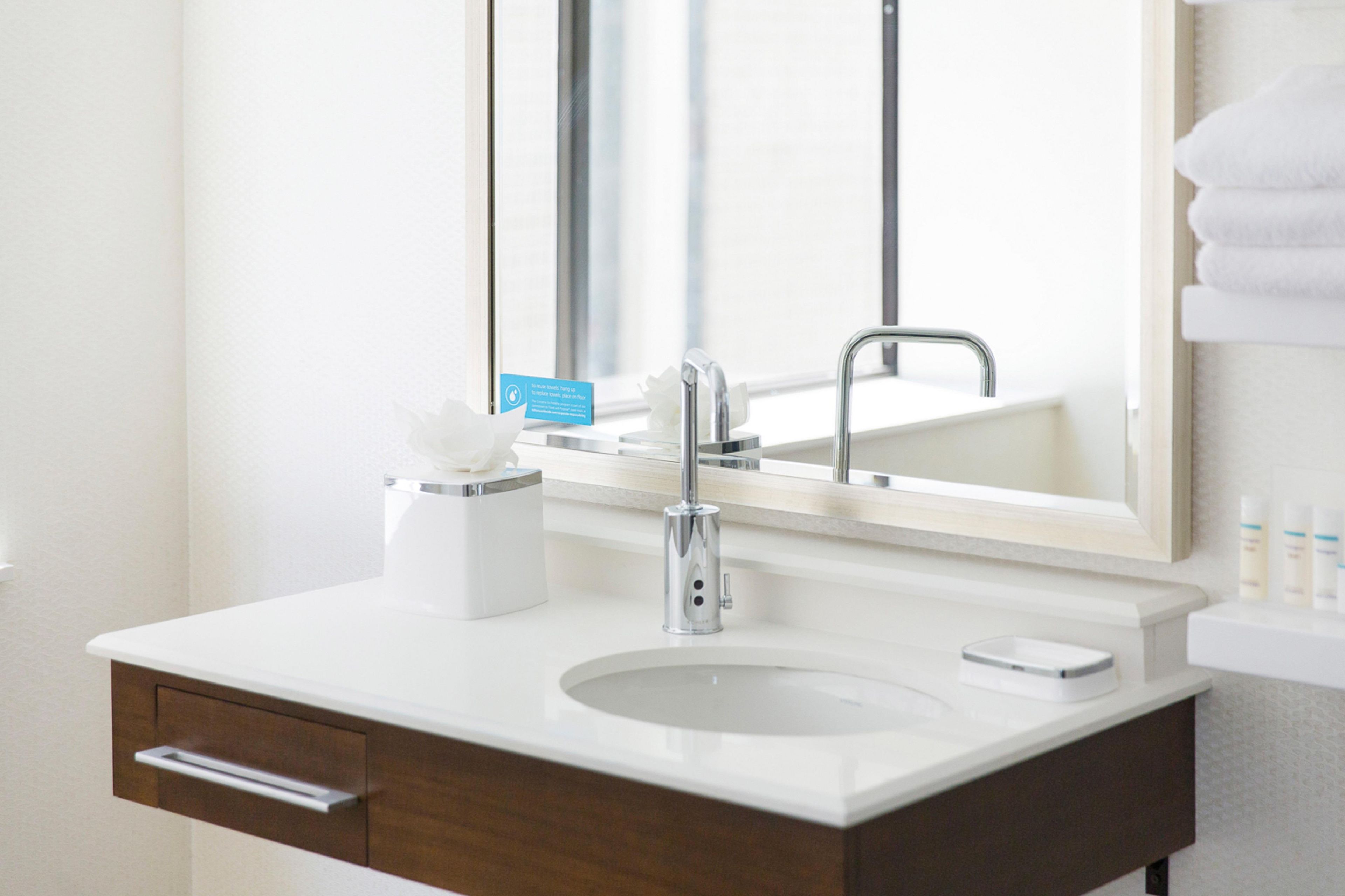 A bathroom with a white sink, a mirror, and a towel rack.