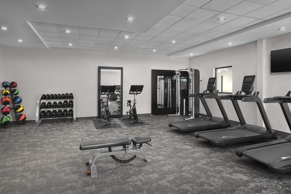 A gym with treadmills, a bench press, and a mirror. - Home2 Suites by Hilton Louisville East/Hurstbourne (Louisville)