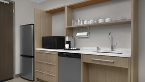 A modern kitchen with a built-in refrigerator, microwave, coffee maker, and dishwasher. - Home2 Suites by Hilton Louisville East/Hurstbourne (Louisville)
