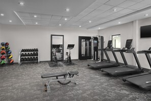 A gym with treadmills, a bench press, and a mirror.