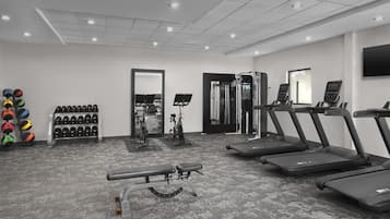 A gym with treadmills, a bench press, and a mirror.